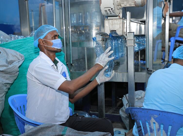 Afi water employee checking the newly crafted bottles and taking them off the rotating machine