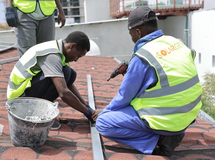 SolarGen construction workers and project managers attaching solar panels to the top of a roof