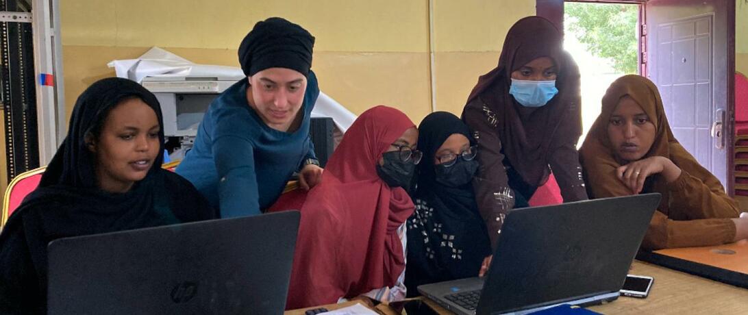 Staff Member Paige Roberts helps several girls with GIS workshop on computers
