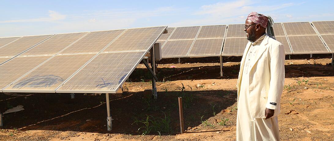 Somali man standing in front of solar panels 
