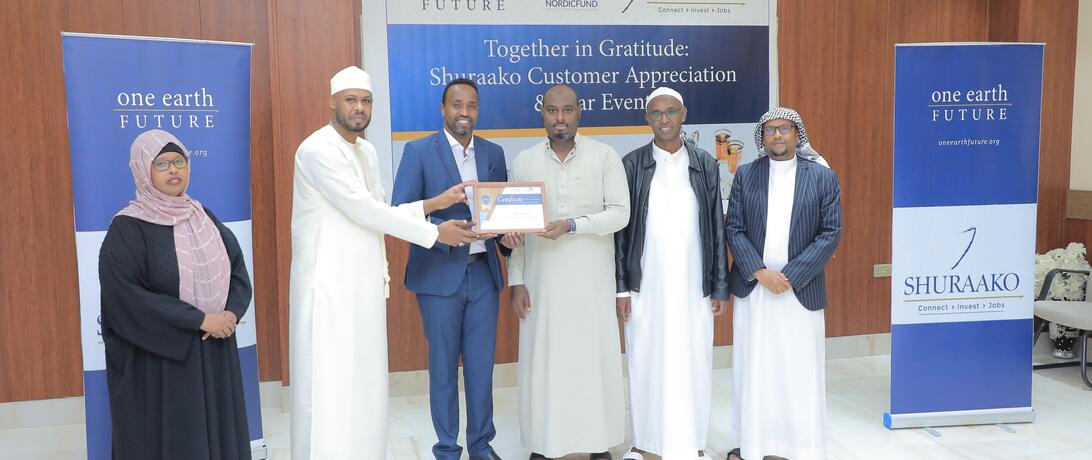Shuraako staff presenting award of loan repayment completion to Shuraako client