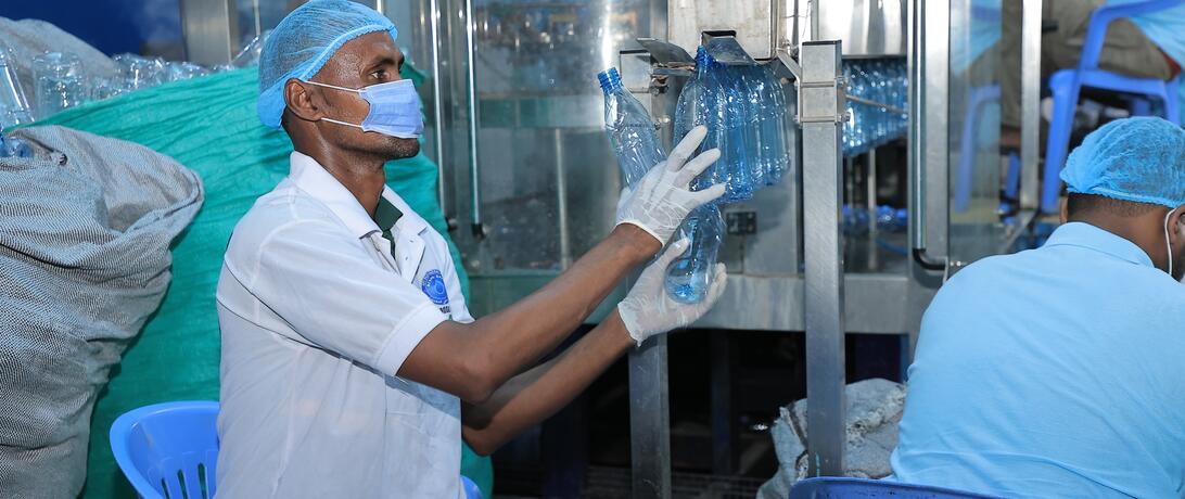 Afi water employee checking the newly crafted bottles and taking them off the rotating machine
