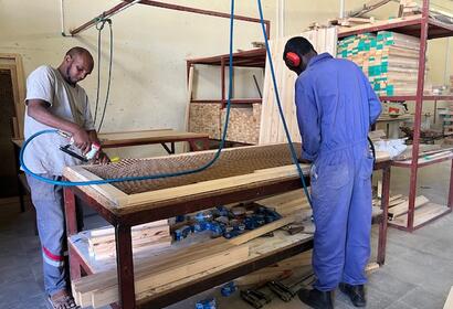 2 employees carving a design into a freshly cut brand new wooden door